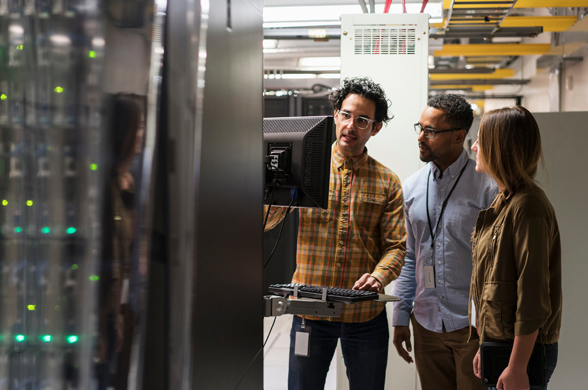 IT professional explaining to two people in a server room