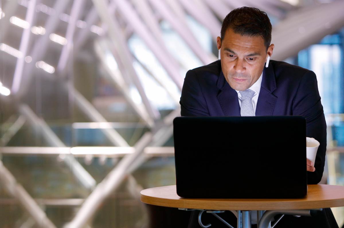Person with earbuds looking at laptop.