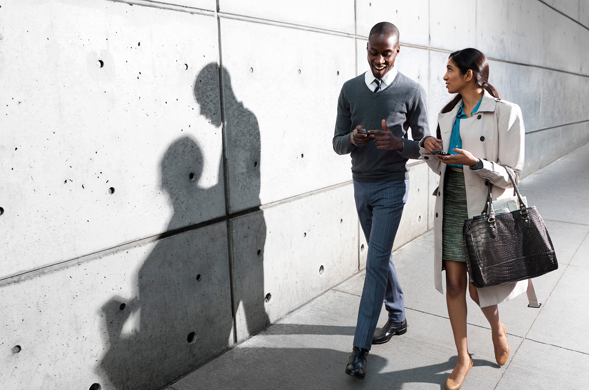 Two people looking at an mobile device while walking