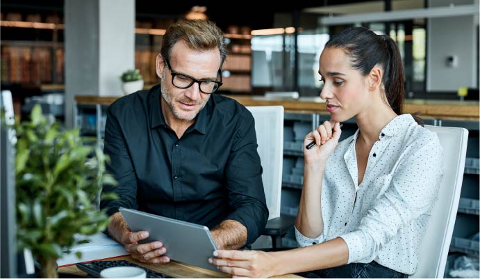 Two professionals meet while looking at a tablet