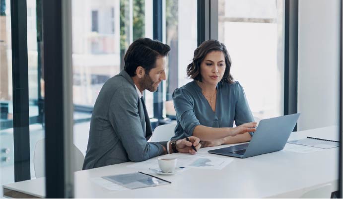 two professionals meet while looking at a laptop
