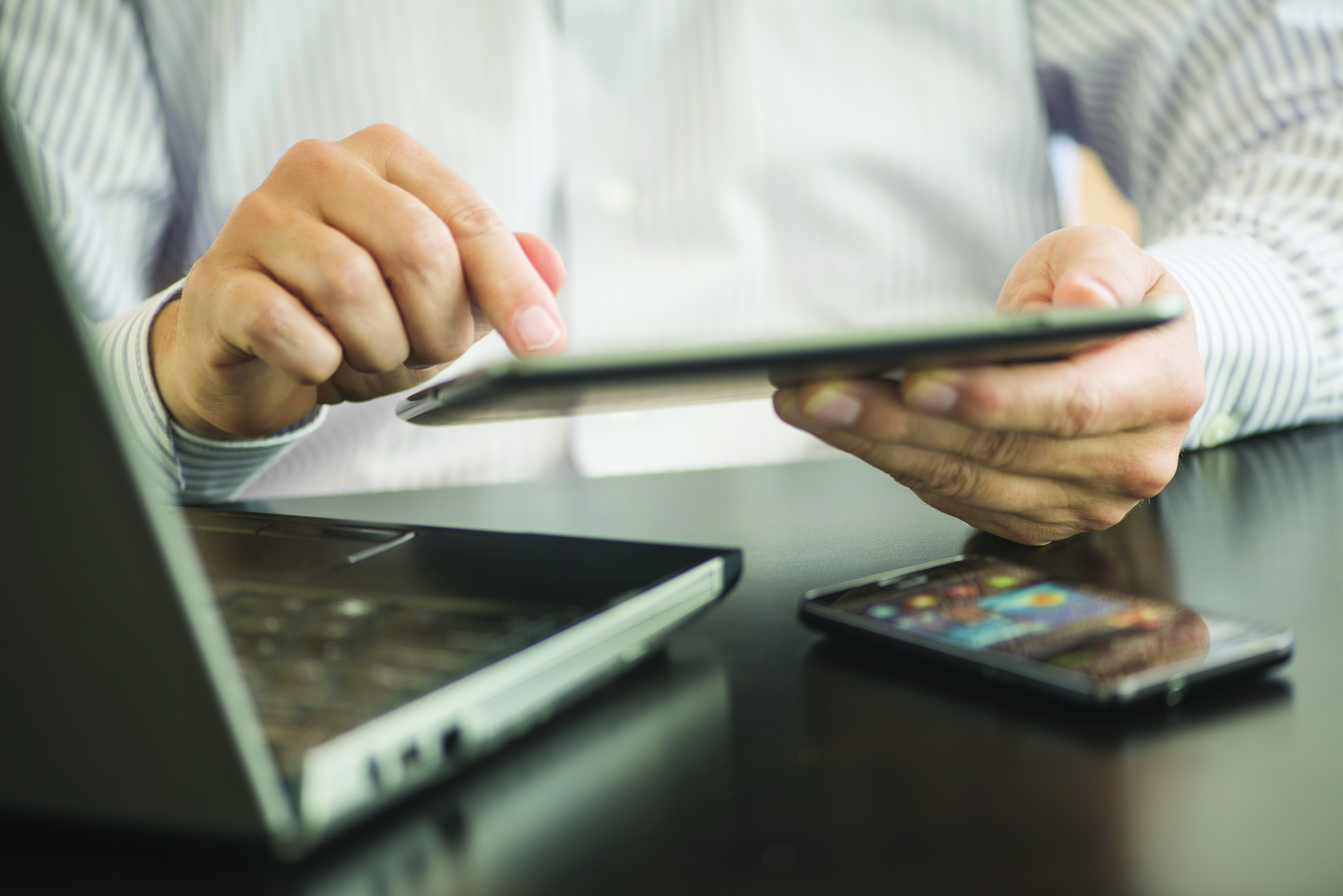 Person managing financial services through tablet, laptop, and phone